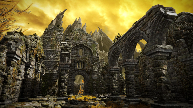 A large stone ruin against a rich yellow clouded sky. Beyond the ruin, jagged peaks rise towards the clouds.