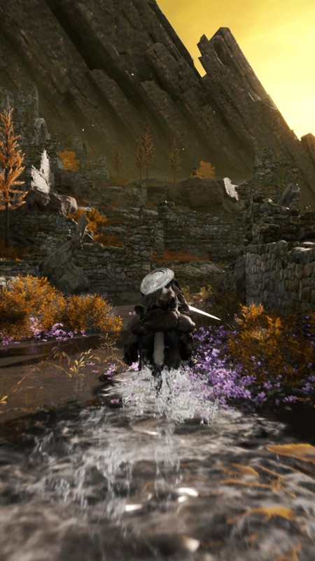 A rear view of a rider urging her horse through the lake, between stone ruins. The water churns in their wake, the brown shrubs and purple flowers blurred in their passing. Ahead, basalt columns rise at jagged angles.