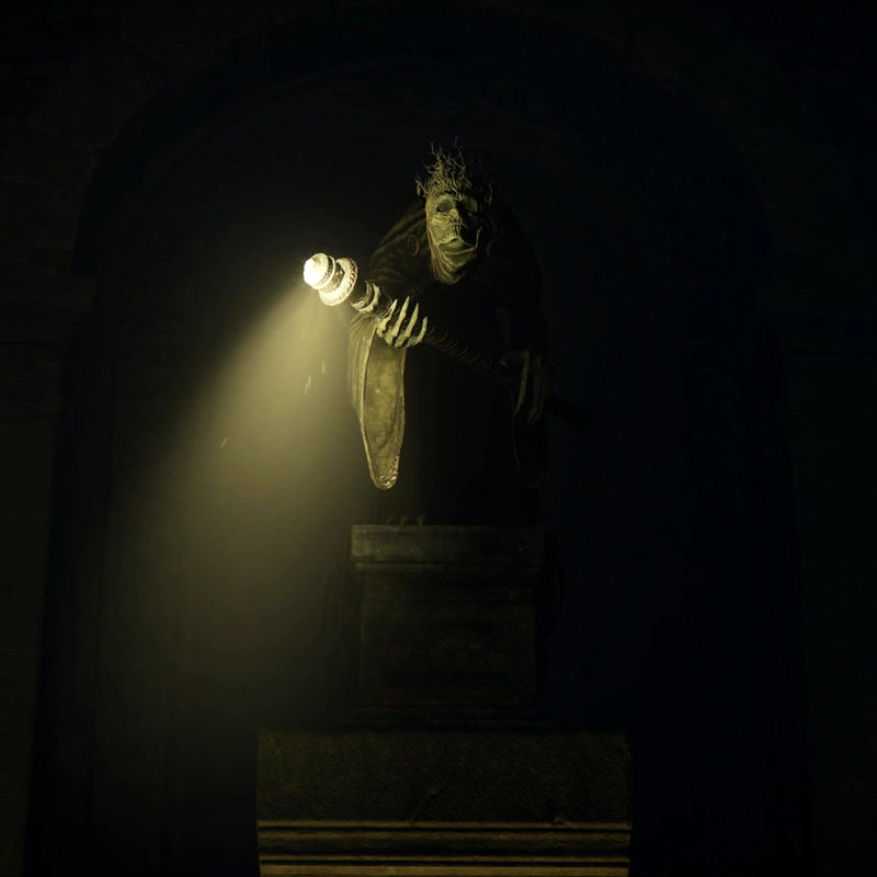 A close-up of a statue of a skeletal figure wearing a heavy robe and a crown of thorns. They are holding a staff emitting a beam of light.