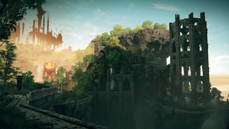 A ruined city built into a series of grey stone cliffs. To the right, a hollow octagonal tower stands draped in hanging vines with a ring of red-leaved trees at its base, while to the right a terraced path leads towards a flaming golem in the distant sunlight between trees.