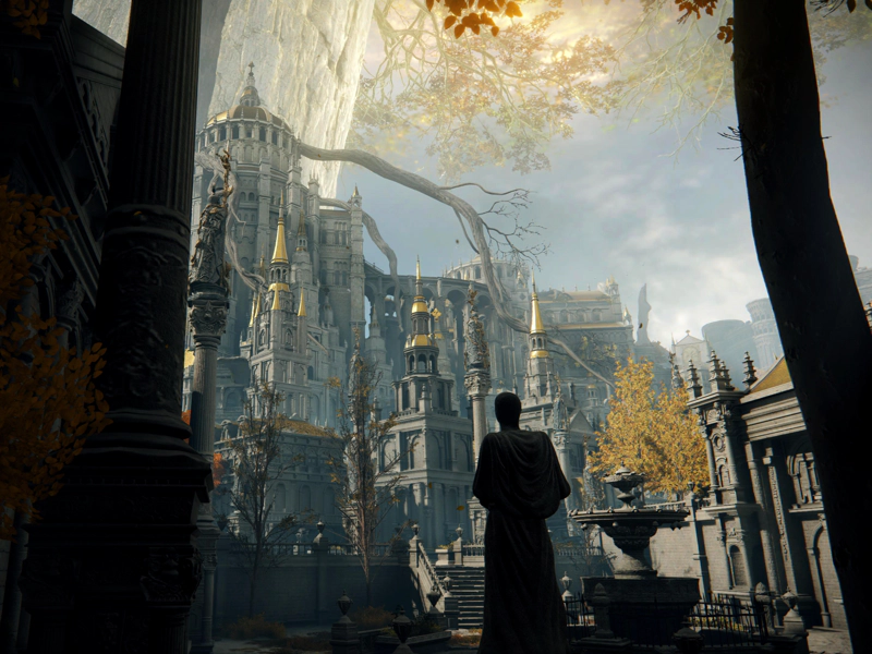 A statue stands silhouetted, penitent, beneath the rising layers of the capital and the radiance of the Erdtree above.