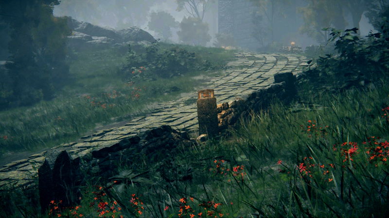 A paved road, curving up towards a castle. A broken-down stone wall tracks the edge of the road, with occasional lit sconces. Grass and red wildflowers dominate the other side of the wall.
