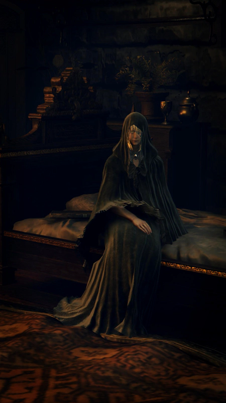 A black-robed woman with an intense gaze, sitting on a rumpled bed. There's an aged rug at her feet.
