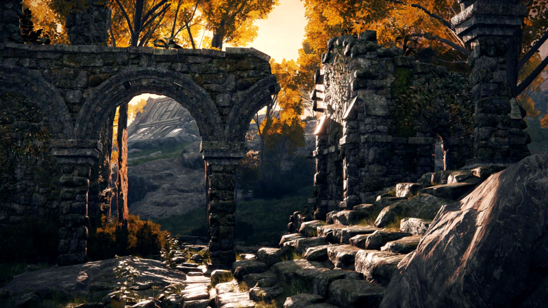 A ruined stone building at sunset. The trees are golden, and the sun gleams off tumbledown stairs and shattered arches.