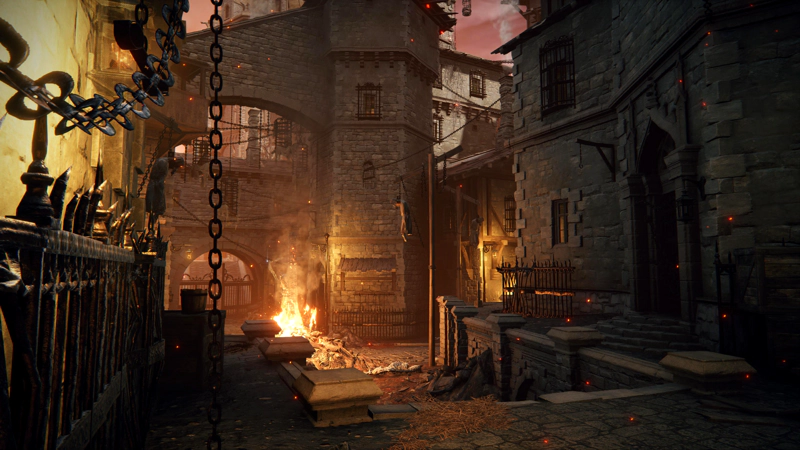 A rough prison town of tangled stone buildings. Chains hang from the structures, some adorned with corpses, and a bonfire burns in the street.