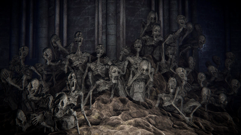 A close-up of what looks like a sculpture of many screaming corpses, set into weathered rock. They are all emaciated, with empty eye-sockets, and many are holding their heads in their hands.