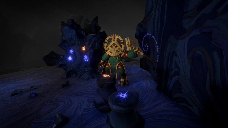 An alien in a space suit, looking at the camera. There are two coloured stones on pillars before her, and alien writing snakes across a wall beside her.